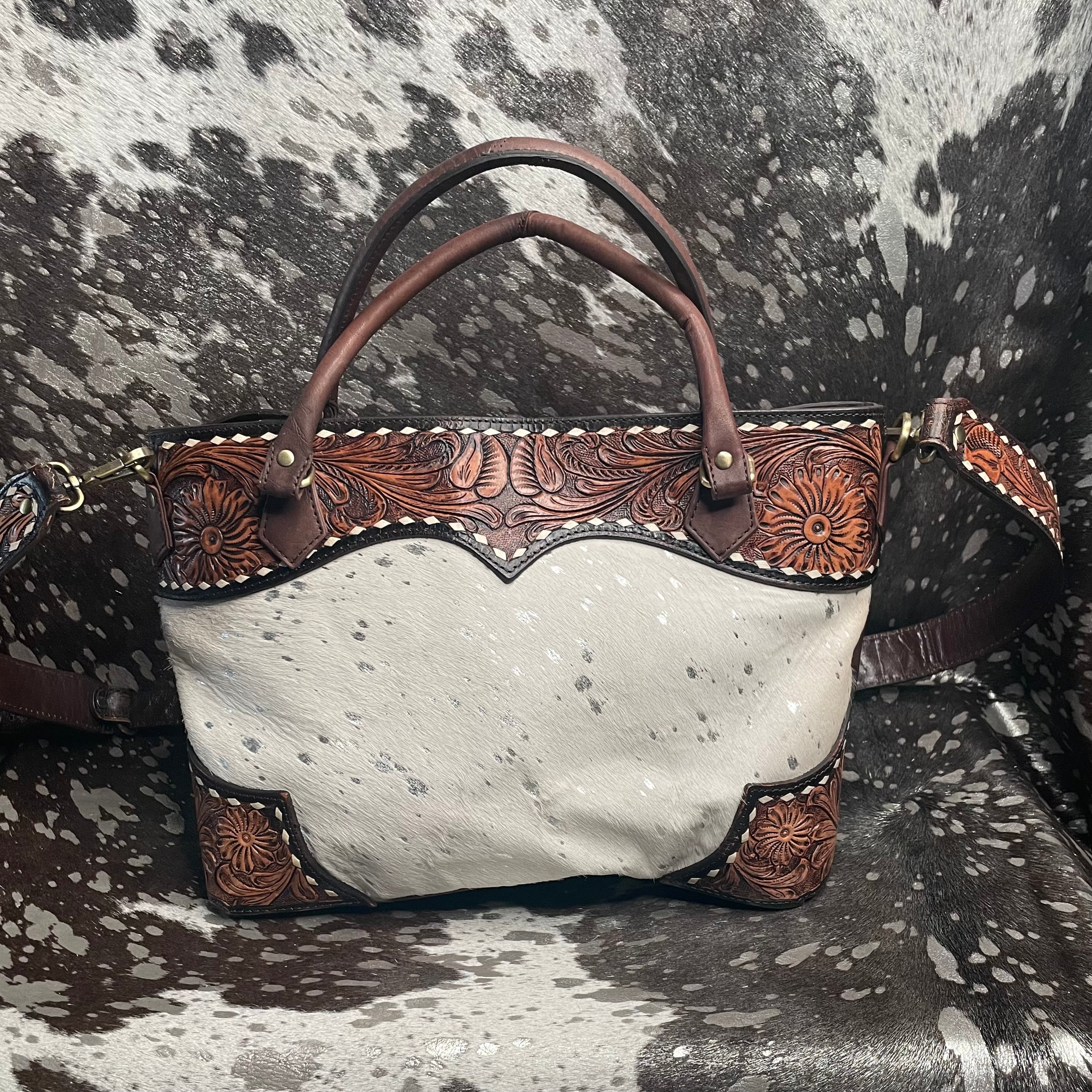 White handbag with brown leather accents on a cowhide background
