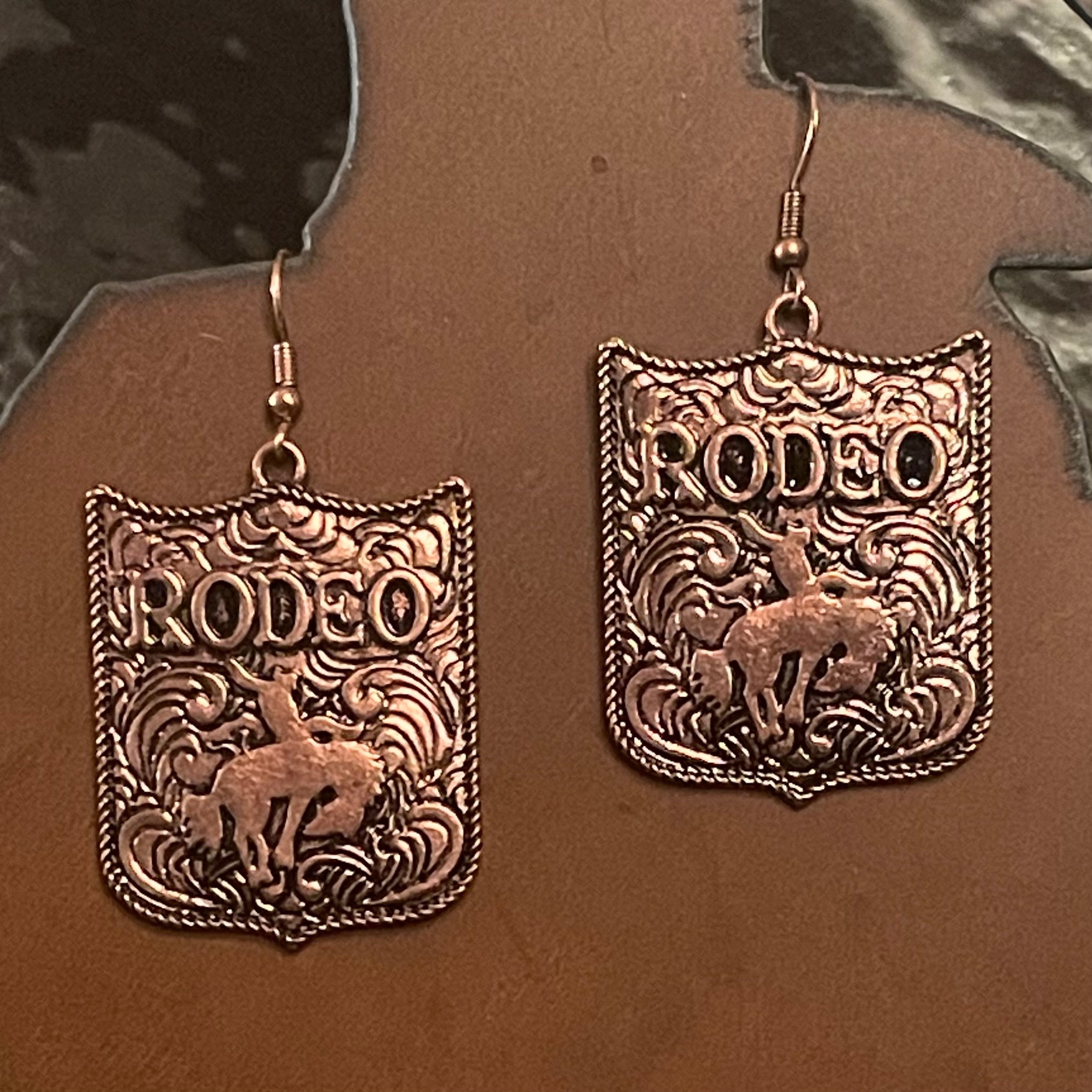 Bronze 'Rodeo' themed earrings on a brown background